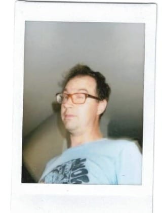 a man with glasses making an ostentatious wink